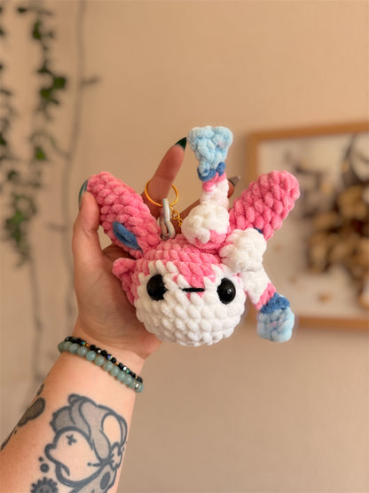 Porte-Clés/Bijou de sac Nymphali au Crochet – Amigurumi Pokémon fait main

Craquez pour ce beau porte-clés/bijou de sac Nymphali (Sylveon) au crochet, une création artisanale unique inspirée de l’univers Pokémon et crochetée à la main par mes soins.

Un Pokémon de collection en version crochet

Crochetée avec de laine chenille et de rembourrage ouate certifiés Oeko-Tex, notre porte-clés Nymphali en crochet combine douceur inégalable et originalité. 