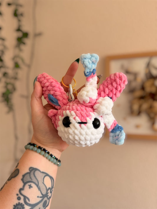 Porte-Clés/Bijou de sac Nymphali au Crochet – Amigurumi Pokémon fait main

Craquez pour ce beau porte-clés/bijou de sac Nymphali (Sylveon) au crochet, une création artisanale unique inspirée de l’univers Pokémon et crochetée à la main par mes soins.

Un Pokémon de collection en version crochet

Crochetée avec de laine chenille et de rembourrage ouate certifiés Oeko-Tex, notre porte-clés Nymphali en crochet combine douceur inégalable et originalité. 